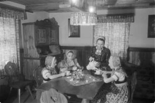 Schleifer Frauen und Mädchen in Schleifer Tracht beim Kaffeetrinken nach dem Verzieren von Ostereiern. : Holcy a žony w Slepjanskej drasće po debjenju jutrownych jejkow při kófejpiću pola Wěrikec w Rownom.