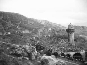 Moschee : Blick auf einen Berghang mit Dorf und Moschee. Eine Männergruppe sitzt vor der Moschee