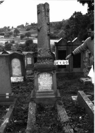 Grabstein 2130 (Index: 100097088) Maße HxBxT: 240x52x42 cm Symbolik: Baumstamm Besonderheit: kulturhistorisch wertvoll / künstl.-formale und hist.-wiss. Gründe (verunglücktes Kind, Inschrift); - Kindergrab: Grabstein 2130