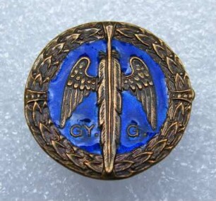 Stenographenabzeichen Ungarn (mit Broschennadel) : Sammlung Beinhorn. Stenographenabzeichen Ungarn (geflügelte Feder und Aufschrift "GY. G." auf blauem Grund im Lorbeerkranz, mit Broschennadel; rückseitig: Berán Bpest). Email, Metall; Durchmesser 24 mm (um 1930; L. Berán). Dresden: SLUB R c 0256