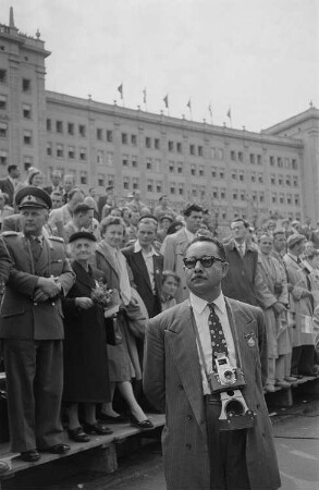 Internationales Publikum auf einer Parade anlässlich des II. Deutschen Turn- und Sportfestes, im Hintergrund die Ringbauten