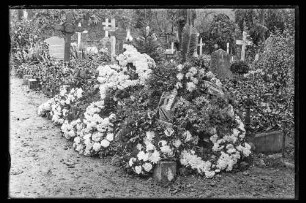 Mit Blumen und Kränzen geschmückte Grabstelle