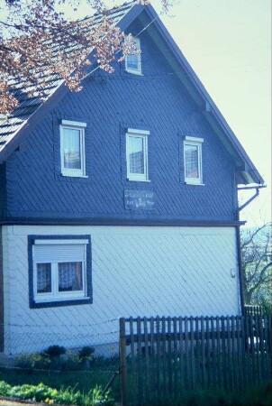 Giebelseite eines Schieferhauses, im Giebel Tafel mit Inschrift