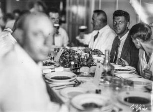 Tafelgesellschaft : Mehrere Personen sitzen an einer Tafel beim Essen.
