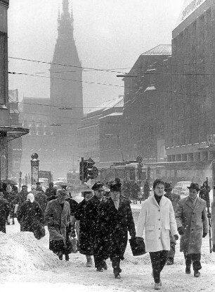 Hamburg-Altstadt. Die Mönckebergstraße im Winter. Reger Fußgängerverkehr bei Schneefall. Im Hintergrund das Rathaus der Freien- und Hansestadt