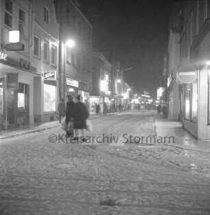 Hindenburgstraße: verkaufsoffener Sonnabend mit Fußgängerzone: vorn Mühlenstraße: rechts und links Wohn- und Geschäftshäuser: dazwischen Fußgänger: Winter: Abend: 8. Dezember 1973