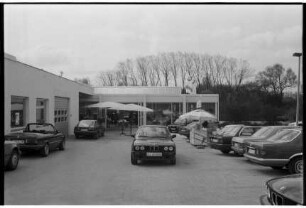 BMW-Niederlassung Adolf Werner: Ostring, Ecke Beimoorweg: Neueröffnung Anbau: Außenansicht: hinten Ausstellungsraum, links Werkstatt: davor auf Außengelände Autos, Sonnenschirme