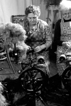 Frauen beim Flachsspinnen in Wohnstube