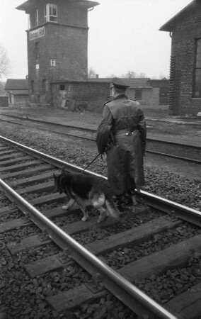 Hanau. Bahnhof. Bundesbahnangehöriger mit Hund beim Ablaufen der Gleisanlage