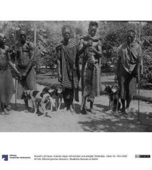 Wahutu-Jäger mit Hunden und erlegter Zibetkatze.
