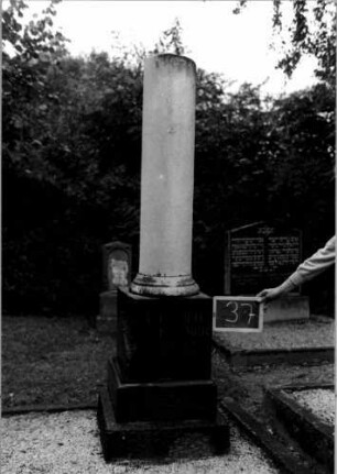 Grabstein 37 (Index: 100110463) Material: Sockel Granit, Säule Marmor Zustand: beschädigt mit Textverlust Maße HxBxT: 200x42x42 cm Beschreibung: gebrochene Säule, getreppter Sockel: Grabstein 37