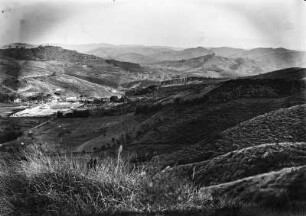 Hügellandschaft : Blick in eine hügelige Landschaft. In der Bildmitte eine Plantage mit Wirtschaftsgebäuden und Pfalnzungen auf den Hängen.