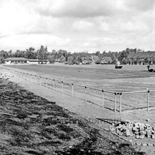 Sporteinrichtungen: Sportanlage am Kortenkamp: Ausbau: Hauptspielfeld: Auftragen des Hartbelages: hinten rechts Arbeiter mit Spezialfahrzeug: vorn rechts Steinhaufen: dahinter Zaun: hinten links Sportlerheim: hinten rechts Wohnhäuser, Rentnerwohnheim und Bäume