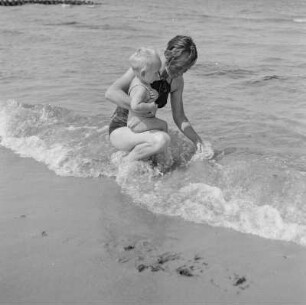 Frau in Bademode und Kleinkind im Meer