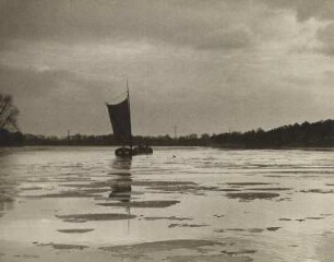Berlin-Tegel. Winterabend auf dem Tegeler See. Ein Segelschiff befindet sich zwischen treibenden Eisschollen auf dem See