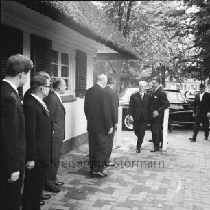 Deutsche Angestellten Akademie (DAA): Ausbildungsstätte des Instituts für Absatzwirtschaft [früher: Groß- und Außenhandel]: Hoisdorfer Landstraße: Besuch des Bundespräsidenten Heinrich Lübke: Ankunft im Beisein von Vorstandsvorsitzendem der DAA Dittmar, Geschäftsführer Lietz, Bürgervorsteher Christoffer Umlauff, Bürgermeister Herbert Schlömp vor dem Akademiegebäude [ehemaliges Kurhaus des Deutschen Rings]: hinten rechts Pkws: im Hintergrund weiteres Gebäude und Bäume
