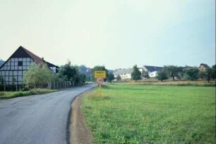 Straße mit Ortsschild; Obstwiesen, große Scheune