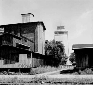 Mühlenbetrieb W. F. Stoltenberg: rechts und links Gebäude: im Hintergrund der neue Silo: davor Bäume: vorn Gleise