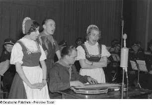 Ein Zitherspieler und drei Sänger in Tracht bei einer Veranstaltung zum Gedenken an die Völkerschlacht, im Hintergrund ein Orchester