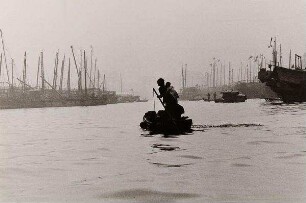 Mutter mit Kind, ein kleines Boot im Hafen steuernd, aus der Serie "Hongkong"