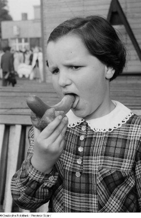 Mädchen mit Bockwurst im Brötchen auf der Kleinmesse am Cottaweg