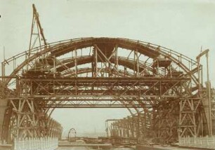 Baustelle Bahnhof Dresden-Neustadt. Stahlhochbauarbeiten durch die Maschinenfabrik Augsburg-Nürnberg - Brückenbau-Anstalt Gustavsburg. Bahnsteighalle (Mittelhalle) mit Laufsteg für Personal an der Hallenschürze, davor Eisenbahnbrücke über die Hansastraße. Ansicht von Südwest : Dresden-Neustadt, Schlesischer Platz. Baustelle Bahnhof Dresden-Neustadt. Stahlhochbauarbeiten durch die Maschinenfabrik Augsburg-Nürnberg - Brückenbau-Anstalt Gustavsburg. Bahnsteighalle (Mittelhalle) mit Laufsteg für Personal an der Hallenschürze, davor Eisenbahnbrücke über die Hansastraße. Ansicht von Südwest