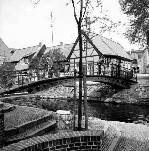 Trave: Stadtarm: Personen auf der Brücke zwischen der Hude und Heiligengeiststraße, vorne Uferterassierung, im Hintergrund Gebäude der Heiligengeiststraße, Blick nach Nordwesten