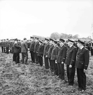 Oetjendorf: Amtfeuerwehrfest: Festwiese: Ehrung für 25-jährige Mitgliedschaft für Gerhard Finnern, Otto Buttgereit, Walter Fobian, Hans Lübke, Wilhelm Rathje, Hugo Taplick, Bernhard Winkelmann, Werner Hinsch und HermannWende durch Kreisbrandmeister Heinz Poschmann und Regierungsrat Alwes: dahinter Feuerwehrmänner: im Hintergrund Häuser und Bäume