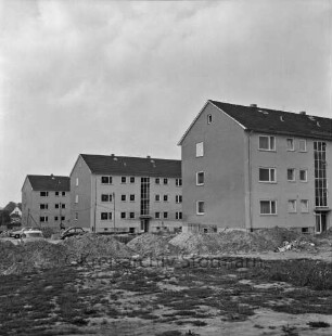 Klosterbergen: Bogenstraße: hinten drei dreigeschossige Wohnblocks vor Fertigstellung: vorn und in der Mitte Sand- und Erdhaufen sowie Reste von Baumaterial auf unbefestigtem Gelände: hinten links Pkws: im Hintergrund links Wohnhaus zwischen Bäumen
