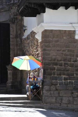 Cusco - Straßenhändler sitzt neben einer Inka-Mauer : Unter einem Sonnenschirm sitzt ein Straßenhändler. Aufgenommen am 30. August 2011 in der einstigen Inka-Hauptstadt Cusco