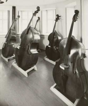 Musikinstrumenten-Museum Markneukirchen. Raum 3: Streichinstrumente (Violenfamilie). Kontrabaßreihe, Ende 17./Anfang 18. Jahrhundert und 1974 (J. Rubner, Markneukirchen). Links hängend: Kopie eines Trumscheits (A. Gläsel, Markneukirchen 1883)