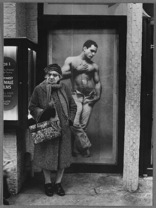 Alte Frau vor einem Plakat mit einem Mann mit nacktem Oberkörper, New York