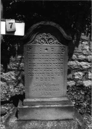Grabstein 7 (Index: 99796553) Material: Sandstein Zustand: gut Maße HxBxT: 98x47x18 cm Beschreibung: Stele, Sockel, Konvexbogenabschluß mit Verdachung Symbolik: Ranken: Grabstein 7