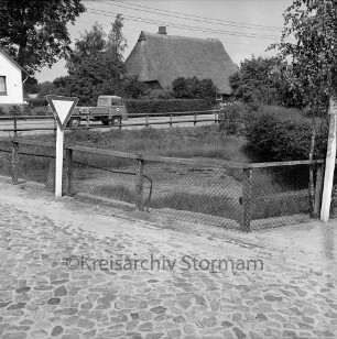Buttertwiete: hinten Alte Landstraße: kleiner Teich: umgeben von Zaun: Kopfsteinpflaster, Vorfahrtsschild: hinten Lkw, Reetdachhaus