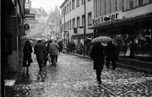 Freiburg: Rathausgasse, Fußgänger mit Regenschirm