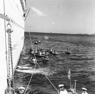 Einheimische mit Ruderbooten an einem Passagierschiff