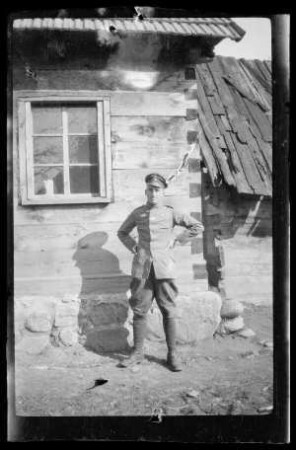 [Paul Sontheimer] vor einem Holzhaus (Ganzkörperbild)