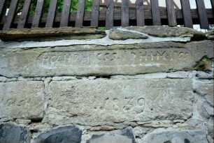 in der Mauer unterhalb des Pfarrhauses Steine mit Inschrift und Jahreszahlen, u.a. 1839