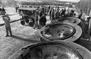 Verschrottung von Kampfpanzern der Nationalen Volksarmee. Freifläche mit umgedreht liegenden Türmen ohne Kanone und Besuchern (wohl Journalisten), im Hintergrund zur Devastierung bereitstehende Panzer : Charlottenhof (bei Görlitz). Panzergerätelager 2 der Nationalen Volksarmee. Verschrottung von Kampfpanzern der Nationalen Volksarmee. Freifläche mit umgedreht liegenden Türmen ohne Kanone und Besuchern (wohl Journalisten), im Hintergrund zur Devastierung bereitstehende Panzer