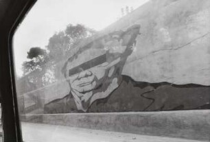 Blick aus einem Autofenster auf ein Graffiti auf einer Mauer