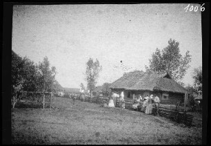 bei Krymno (=Krymne, Ukraine): Einheimische auf einer Dorfstraße neben einem reetgedeckten Holzhaus
