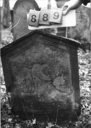 Grabstein 889 (Index: 99751184) Material: Sandstein Zustand: abgeblätt/verwitt/fast völl. Textverlust Maße HxBxT: 76x57x8 cm Beschreibung: Stele, giebelartiger Abschluß mit Verdachuing, Schriftfeld eingetieft: Grabstein 889