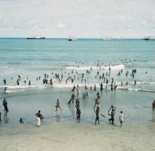 Accra. Ussher Fort : Accra (Ghana). Badende am Strand bei Ussher Fort und auf Reede liegende Frachtschiffe, 20. April 1959