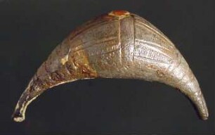 Fibel mit vollem, geschlossenem, geschwelltem Bügel; gravierte Streifen und konzentrische Kreise auf dem ... Bügel; Nadel fehlt; an den Bügel festgerostet ein Ring mit gravierten Linien