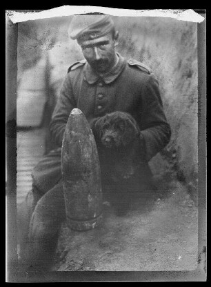 Soldat mit jungem Hund hinter Geschützmunition