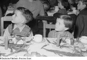 Kinder an einer gedeckten und geschmückten Tafel bei der Weihnachtsfeier des Verlags Volk und Wissen