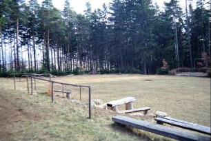 Festplatz im Wald mit kleiner Bühne und Sitzgelegenheiten
