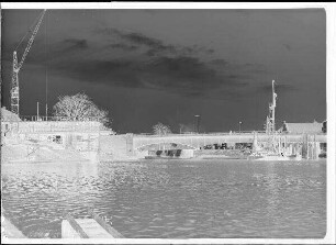Staustufe Schweinfurt. Straßenbrücke. Lehrgerüst und fertige Schalung für den Überbau auf der Bleichraseninsel. In Bildmitte Rammung der Baugrubenumschließung für Pfeiler 1. Schweinfurter Oberwasserstand = 412 cm.