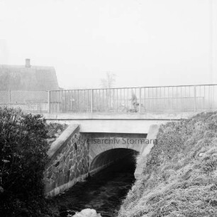 Beek: Brücke der Bundesstraße B 75 mit Fahrradfahrer: vorn Böschungen: dahinter Häuser