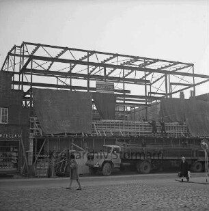 Firma Carl Hoffmann: Hindenburgstraße: Elektrohandel: Neubau: Aufbau des Stahlgerüsts: davor Bauzaun und Lkw: vorn zwei Frauen: links Wohn- und Geschäftshaus des Haushaltswarengeschäfts Otto Möller
